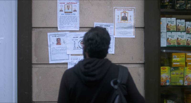 Siva looking at the obituaries posted on street walls at La Chapelle